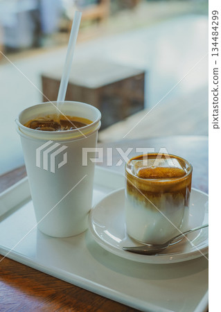 Ice Cream Latte and Paper Cup Iced Americano on a Cafe Tray by the Window 134484299