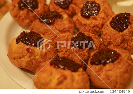 Baked Scones Topped with Berry Jam Served on a Plate under Bright Lighting Baked Scones Topped with Berry Jam Served on a Plate under Bright Lighting 134484949