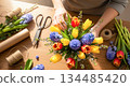 Floral arrangement process with vibrant tulips and hyacinths being crafted into a beautiful bouquet on a wooden table with tools nearby 134485420
