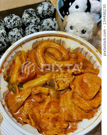 Rose yeoptteok with chewy rice cakes in creamy spicy sauce served alongside jumeok bap rice balls, creating a flavorful combination of rich, spicy, and savory textures in a comforting Korean meal 134486230