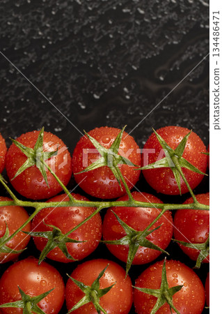 wet ripe red round tomatoes on a black slate board, sweet fresh round tomatoes covered with water droplets lie on a board after harvesting 134486471