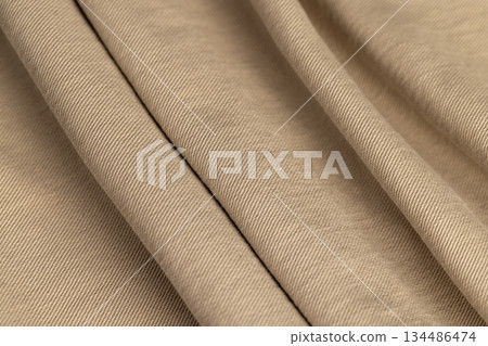 a new thin beige denim fabric from trousers, details of the fabric from which trousers or other clothes are sewn 134486474