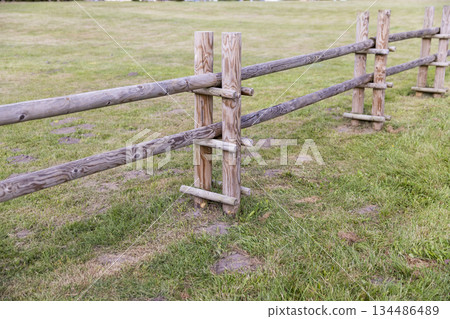 part of a new wooden fence made of logs and roundwood in rural areas, primitive fencing against large animals in rural areas during the summer season, cloudy weather part of a new wooden fence made of logs and roundwood in rural areas, primitive fencing against large animals in rural areas during the summer season, cloudy weather 134486489