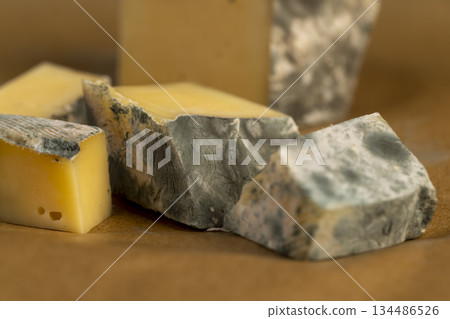 an old spoiled orange cheese with colorful mold, an inedible and dangerous cheese that was spoiled during the improper storage, the cheese is covered with mold dangerous to health 134486526