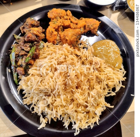 Nasi kebuli with fragrant spiced rice cooked with rich seasonings, served with tender meat, fried shallots, and garnishes, creating a flavorful and aromatic traditional Middle Eastern-inspired dish 134486867