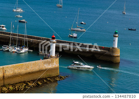 Sunlit Harbor Scene With Sailboats, Twin Lighthouses, And Calm Blue Water 134487810