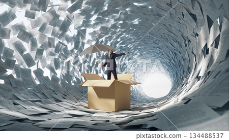 Surreal concept with a man in a suit standing in a box surrounded by swirling papers and holding an umbrella in a creative space 134488537