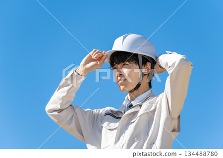 Young man in work clothes, blue sky Young man in work clothes, blue sky 134488780