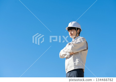 Young man in work clothes, blue sky Young man in work clothes, blue sky 134488782