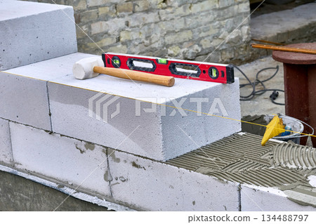 Wooden hammer, measuring level for fitting building blocks of bricks Wooden hammer, measuring level for fitting building blocks of bricks 134488797