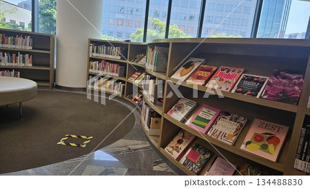 A polished library interior with marble floors and sunlit windows showcases curated cookbooks and lifestyle titles, inviting readers into a calm, organized space for learning and discovery 134488830