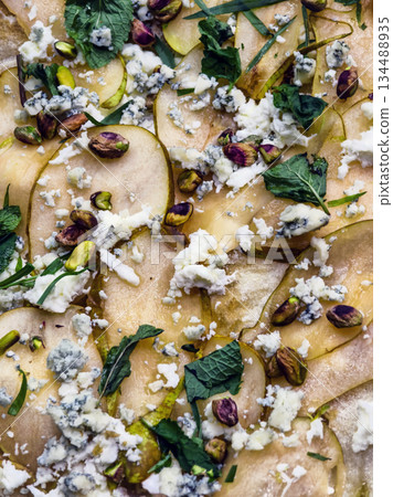 pizza Sliced pear with toppings of cheese, nuts, and herbs 134488935