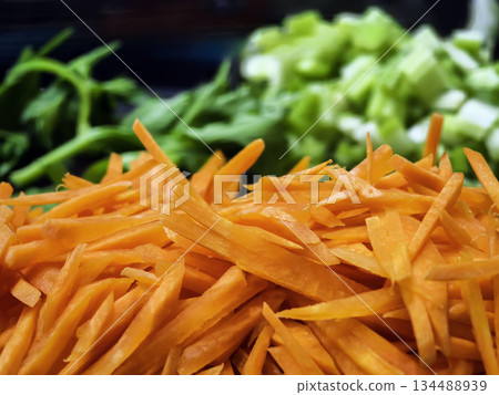 Slicing carrots and celery for a fresh salad in a kitchen during the day 134488939