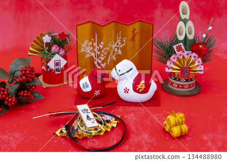 A gorgeous New Year's image featuring a red and white horse figurine, kadomatsu (New Year's pine decorations), and a gold folding screen against a vibrant red background. A gorgeous New Year's image featuring a red and white horse figurine, kadomatsu (New Year's pine decorations), and a gold folding screen against a vibrant red background. 134488980