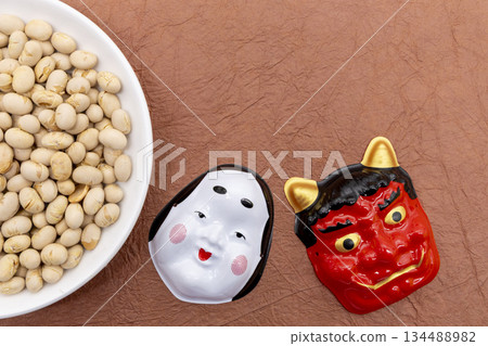 Roasted soybeans on a white plate placed on a brown Japanese paper background and red demon and Okame masks Setsubun image Roasted soybeans on a white plate placed on a brown Japanese paper background and red demon and Okame masks Setsubun image 134488982