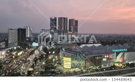 Metropolitan Mall glows at sunset amid bustling traffic, brand signage, and high-rise silhouettes, capturing the vibrant pulse of urban life and commercial energy in a dynamic cityscape Metropolitan Mall glows at sunset amid bustling traffic, brand signage, and high-rise silhouettes, capturing the vibrant pulse of urban life and commercial energy in a dynamic cityscape 134489045
