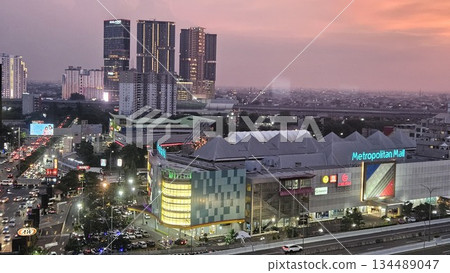 Metropolitan Mall glows at sunset amid bustling traffic, brand signage, and high-rise silhouettes, capturing the vibrant pulse of urban life and commercial energy in a dynamic cityscape 134489047