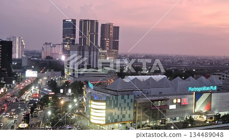 Metropolitan Mall glows at sunset amid bustling traffic, brand signage, and high-rise silhouettes, capturing the vibrant pulse of urban life and commercial energy in a dynamic cityscape Metropolitan Mall glows at sunset amid bustling traffic, brand signage, and high-rise silhouettes, capturing the vibrant pulse of urban life and commercial energy in a dynamic cityscape 134489048