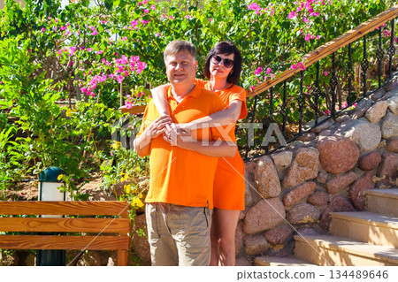 An adult man and woman in orange clothes are hugging tenderly 134489646