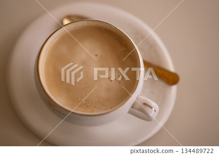 Coffee cappuccino elegant overhead view of creamy latte in white porcelain cup with golden spoon 134489722