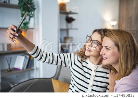 Two Women Sitting on a Couch Taking a Selfie 134490832