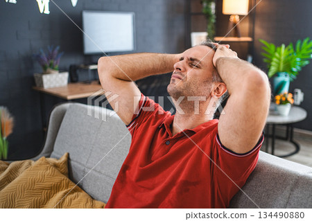 Man sitting alone at home looking sad and distraught Man sitting alone at home looking sad and distraught 134490880