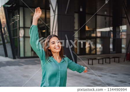 Young businesswoman celebrating success in front of modern office building 134490994