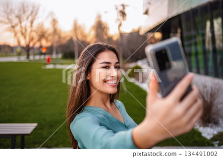 Young woman taking a selfie with smartphone in a park 134491002