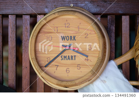 A wooden clock hangs on a wooden wall, with the words WORK and SMART replacing the numbers 11 and 5. The hands point to almost half past nine 134491360