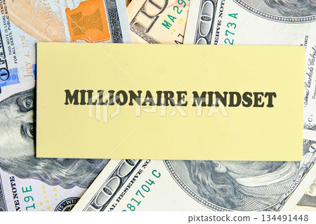 A yellow card displays the words Millionaire Mindset, surrounded by a vibrant and textured background of One Hundred Dollar bills, evoking thoughts of ambition and achievement 134491448