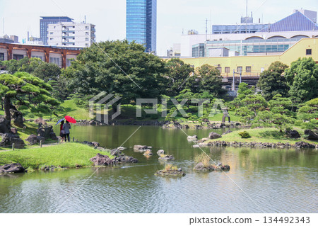 A Japanese garden scene with Japanese umbrellas and stone lanterns reflected in the pond at the Kyu-Shiba Rikyu Gardens A Japanese garden scene with Japanese umbrellas and stone lanterns reflected in the pond at the Kyu-Shiba Rikyu Gardens 134492343