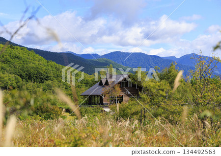 A distant view of a wooden cafe in Norikura Highlands, surrounded by green mountains and grasslands A distant view of a wooden cafe in Norikura Highlands, surrounded by green mountains and grasslands 134492563