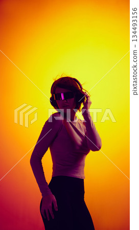 Woman in futuristic glasses and headphones posing in digital light. 134493156