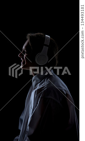 Smiling man in headphones standing on black background. Smiling man in headphones standing on black background. 134493181