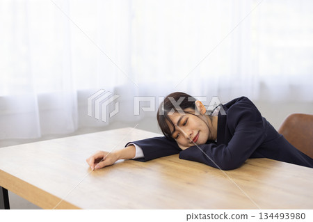 Young Japanese businesswoman sleeping face down at her desk 134493980