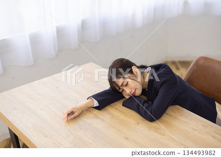 年輕的日本女商人臉朝下趴在辦公桌上睡覺 134493982