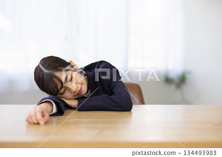 年輕的日本女商人臉朝下趴在辦公桌上睡覺 134493983