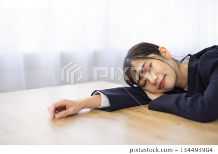 年輕的日本女商人臉朝下趴在辦公桌上睡覺 134493984