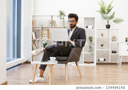 An Arab businessman is working on his laptop in a modern office setting, looking focused and professional 134494148