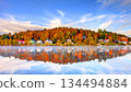 Scenic autumn landscape of Saranac Lake village in Adirondack Mountains New York featuring colorful fall foliage, historic waterfront houses and perfect misty water reflection under blue sky. 134494884
