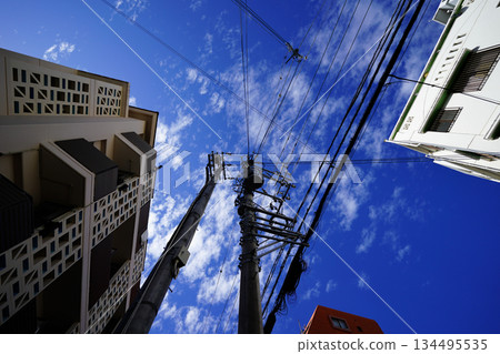 Looking up at the cityscape, blue sky and power lines, urban composition, intersecting lines, everyday sky Looking up at the cityscape, blue sky and power lines, urban composition, intersecting lines, everyday sky 134495535