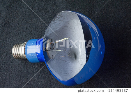 A broken glass light bulb with an exposed filament 134495587