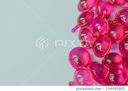 Bright pink hair capsules border on the left side of a clean light background, providing generous copy space for text, promotional cosmetic health care advertising Bright pink hair capsules border on the left side of a clean light background, providing generous copy space for text, promotional cosmetic health care advertising 134495805