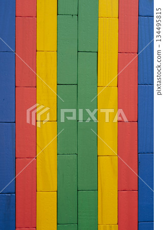 Close-up of a wall made from brightly colored wooden toy blocks arranged in a neat geometric pattern and texture, suitable for a background Close-up of a wall made from brightly colored wooden toy blocks arranged in a neat geometric pattern and texture, suitable for a background 134495815