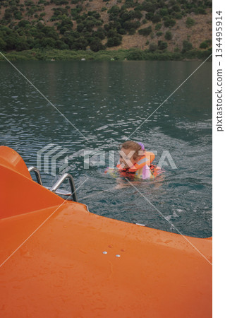 Water safety: child in a life jacket securely holding the tow line of a water bicycle Water safety: child in a life jacket securely holding the tow line of a water bicycle 134495914