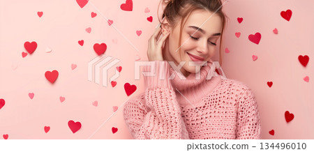 Close-up portrait of young woman in pink sweater with hearts background for valentine's day 134496010