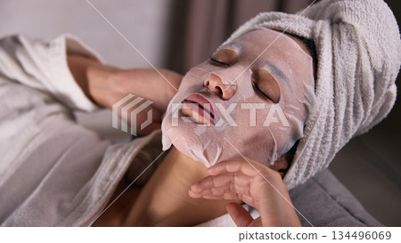Relaxed woman with sheet mask resting at home. Relaxed woman with sheet mask resting at home. 134496069