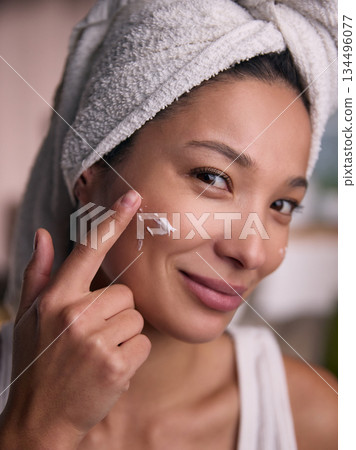 Close-up woman applying facial cream on cheek. 134496077