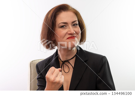 The woman in the black jacket clenches her fist, showing determination and a winning attitude. The woman in the black jacket clenches her fist, showing determination and a winning attitude. 134496100