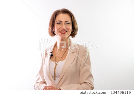 A woman in an elegant jacket poses for a business portrait in a studio. A woman in an elegant jacket poses for a business portrait in a studio. 134496119